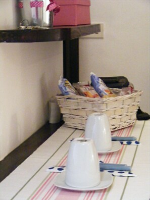 A table with plates, cups, and a basket of snacks.