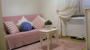 A cozy room with a pink sofa, a small white table, and a white radiator. - Trastevere, Pretty,central,economic (Rome)