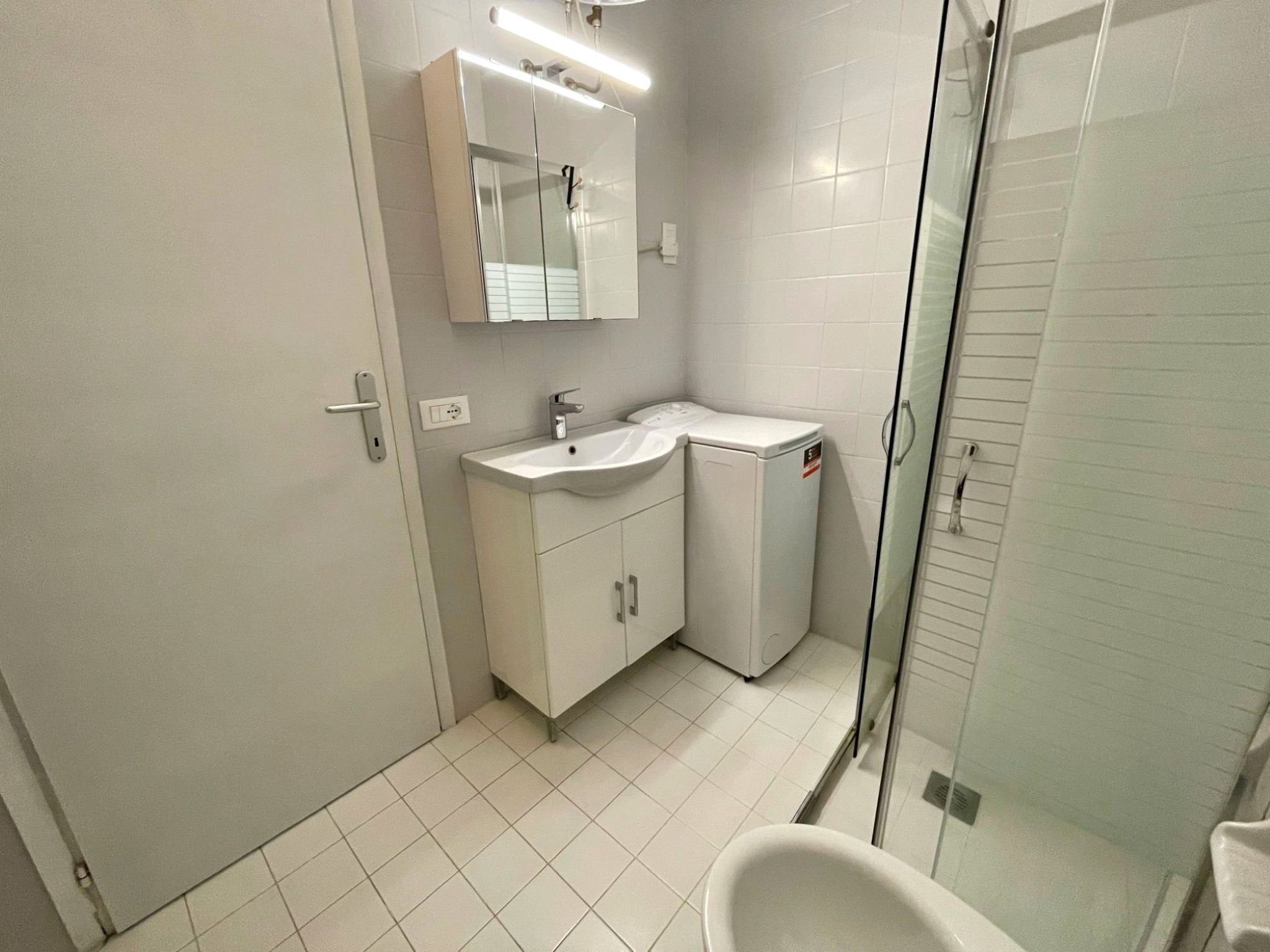 A modern bathroom with a glass shower enclosure, a white sink, and a toilet.
