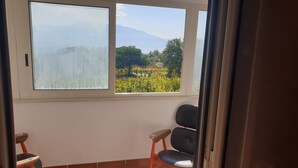 A room with a large window offering a view of a vineyard and mountains. - Casale Rendine Villa (Boscotrecase)