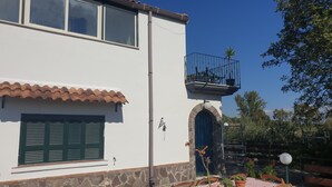 A two-story building with a white facade, green shutters, and a stone base. - Casale Rendine Villa (Boscotrecase)