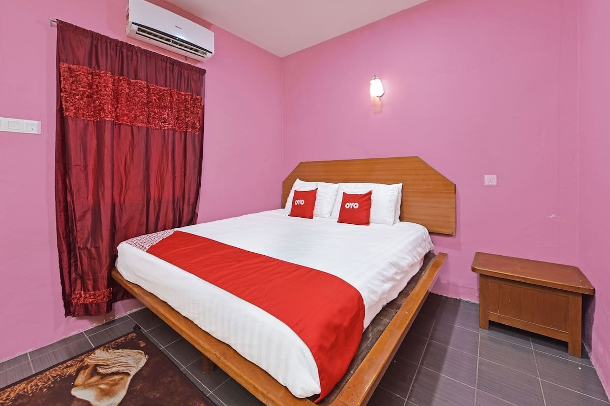 A bedroom with a bed, a nightstand, an air conditioner, and a wall-mounted light fixture.