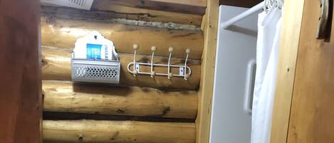 A wooden cabin bathroom with a toilet, sink, and shower.