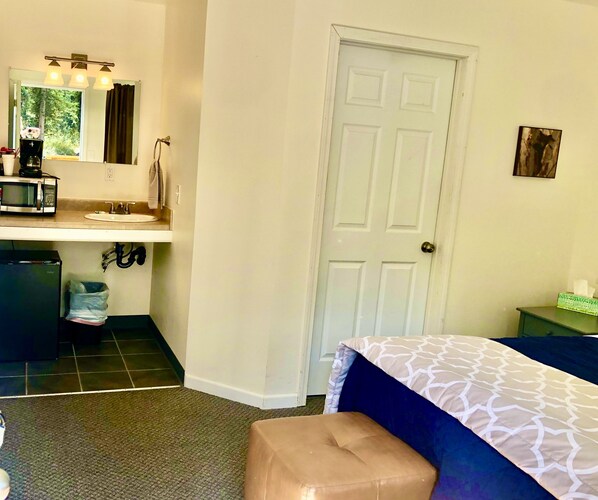 Un dormitorio con cama, mesita de noche, cómoda, espejo y puerta.