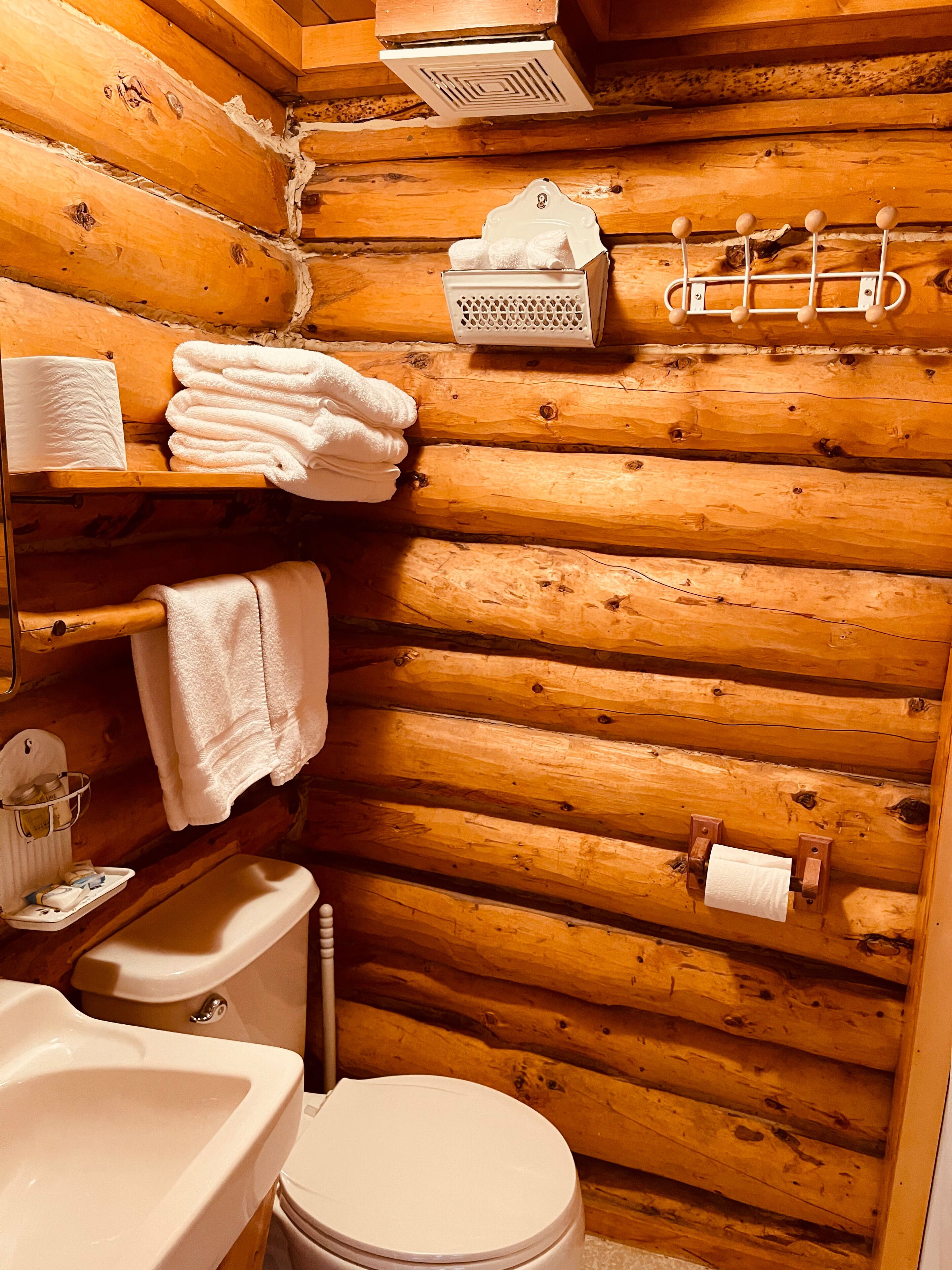 Een houten badkamer met een toilet, wastafel en handdoekhouder.