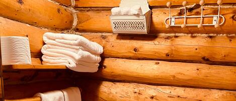 Een houten badkamer met een toilet, wastafel en handdoekhouder.