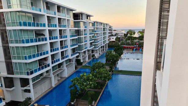 A multi-story hotel with balconies, a swimming pool, and a view of the sea. - My Resort Hua Hin Water Park Bunk Bed Family Pool View (Hua Hin)