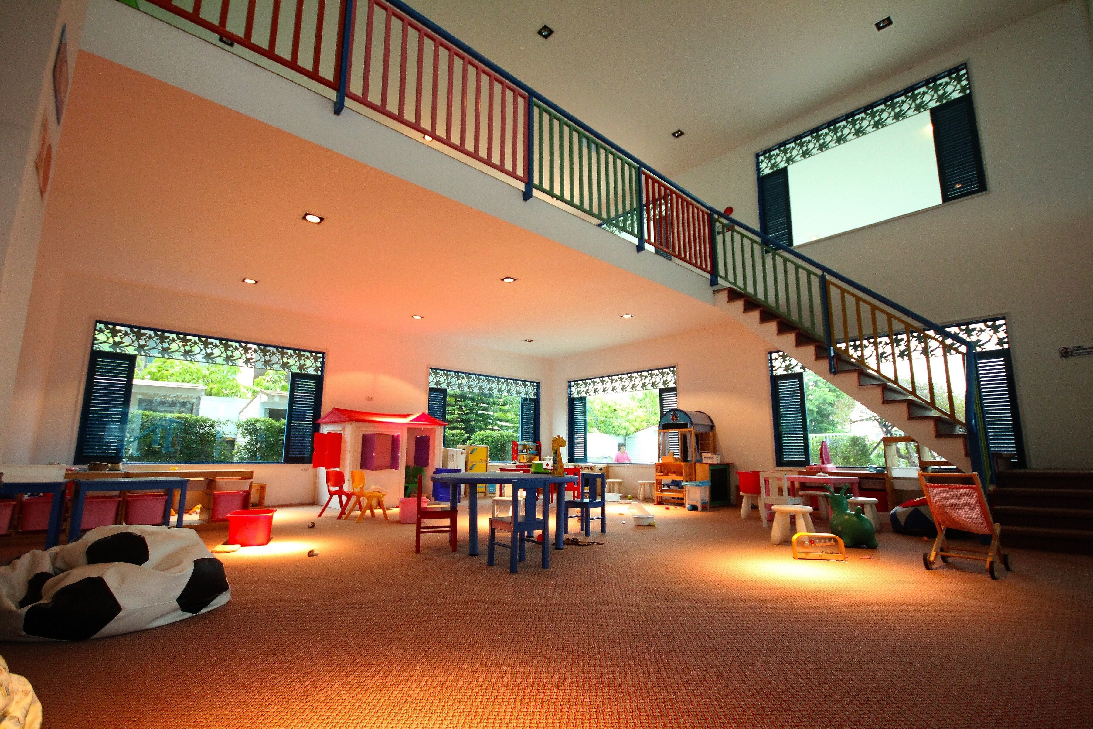 Ein geräumiger Raum mit hoher Decke, einer Treppe und einem großen Fenster.