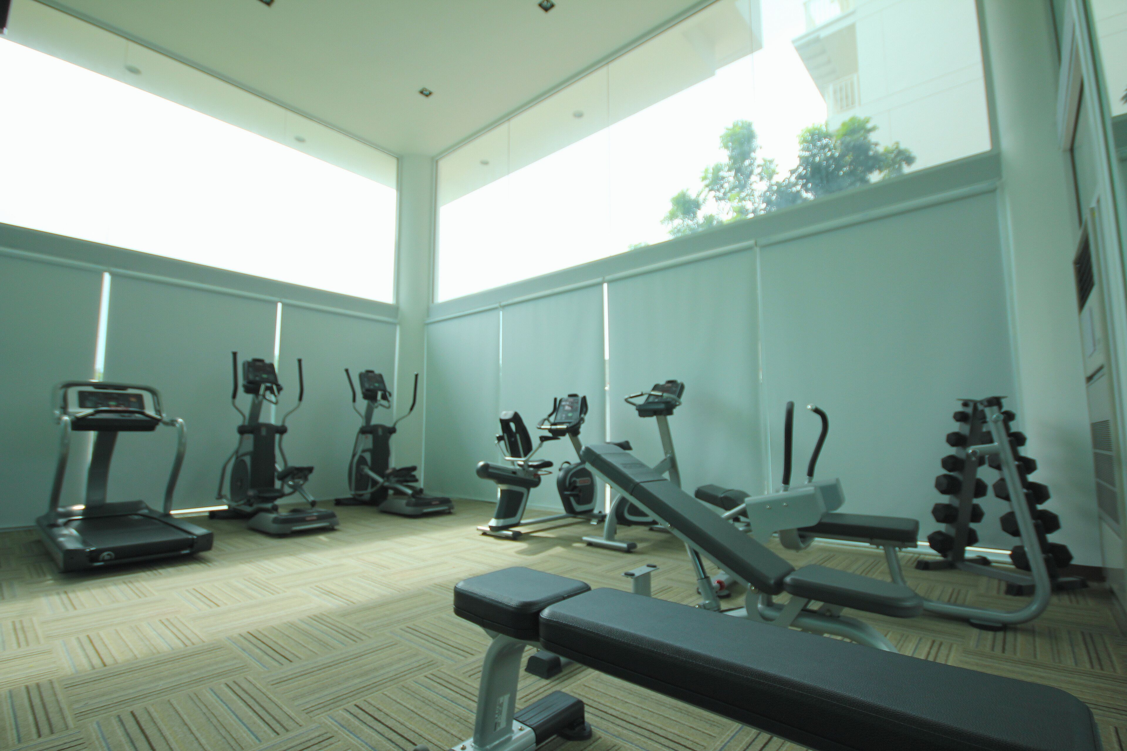 Une salle de sport équipée de tapis de course, de vélos elliptiques et de poids libres.