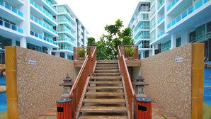 A staircase leading to a pool area, flanked by stone walls and blue balconies. - My Resort Hua Hin Water Park Bunk Bed Family Pool View (Hua Hin)