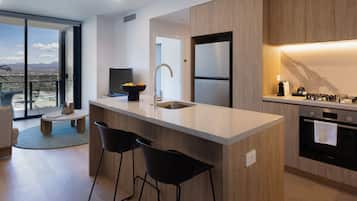 Une cuisine moderne dotée d’un grand îlot central, de tabourets de bar, d’un four encastré et offrant une vue sur la ville.