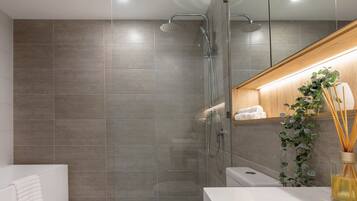 A modern bathroom with a glass shower enclosure, a white sink, and a wooden vanity.