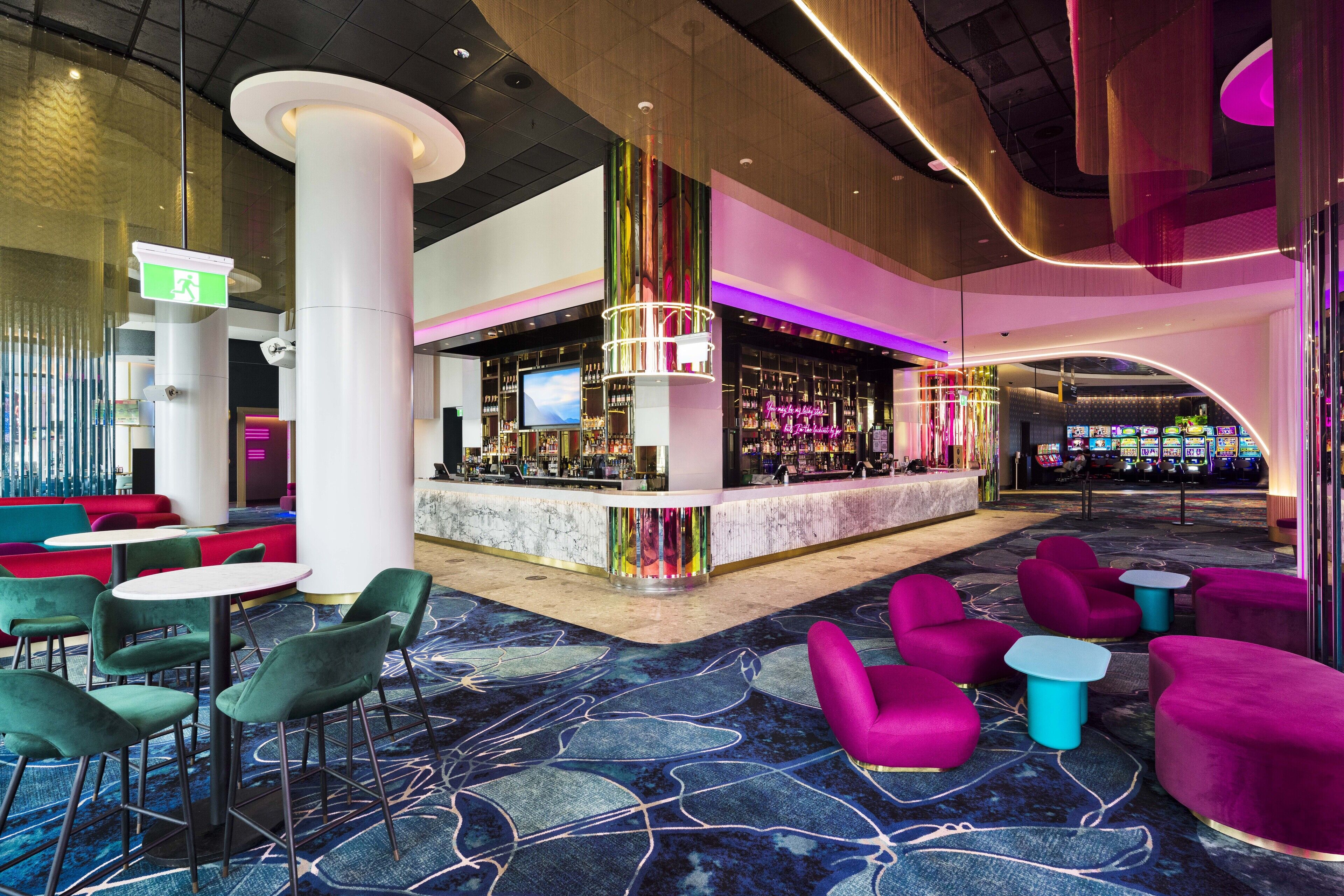 Un hall d’hôtel moderne doté d’un bar, d’espaces aménagés avec des sièges et d’un grand écran.