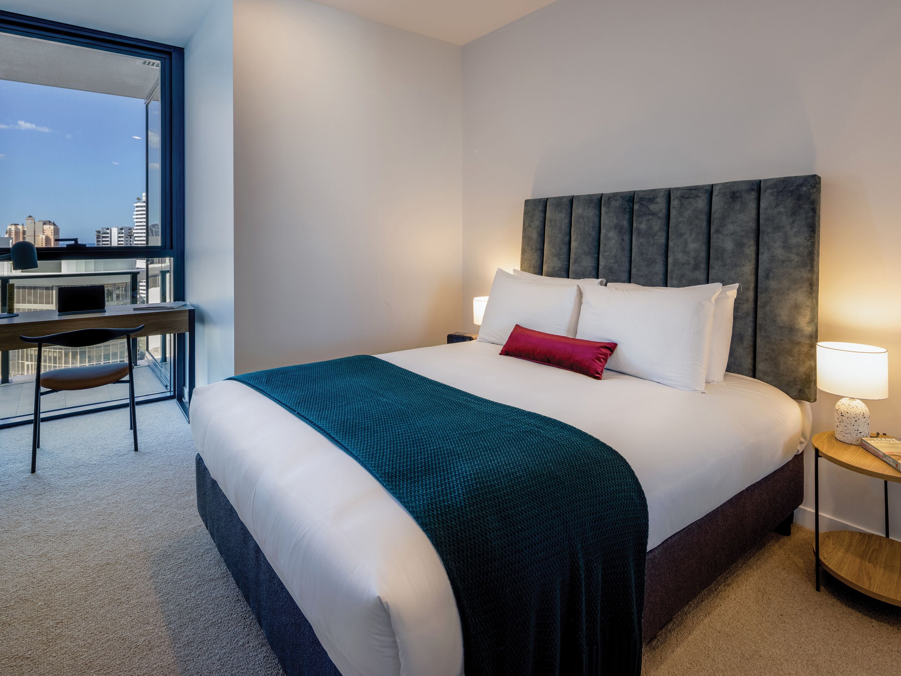 Une chambre d’hôtel moderne avec un grand lit, un bureau et une vue sur le paysage urbain.