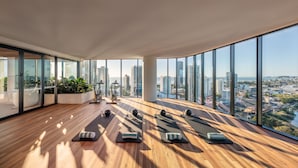 A spacious room with large windows, exercise equipment, and potted plants. - The Star Residences Gold Coast (Broadbeach)