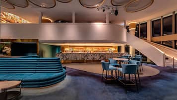 Eine moderne Bar mit einer gebogenen Sitzgruppe, einer Marmor-Theke und einer Treppe zu einer erhöhten Ebene.