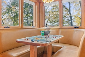 Eine Sitzecke mit Holztable und Tisch, gedeckt für Brettspiele, eine Schüssel Popcorn und eine Sprite-Dose.