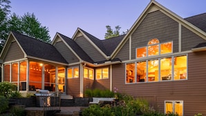 A two-story house with a covered patio, a barbecue grill, and a well-maintained garden.