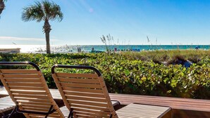 Un salon de plage avec des chaises en bois et vue sur l’océan.
