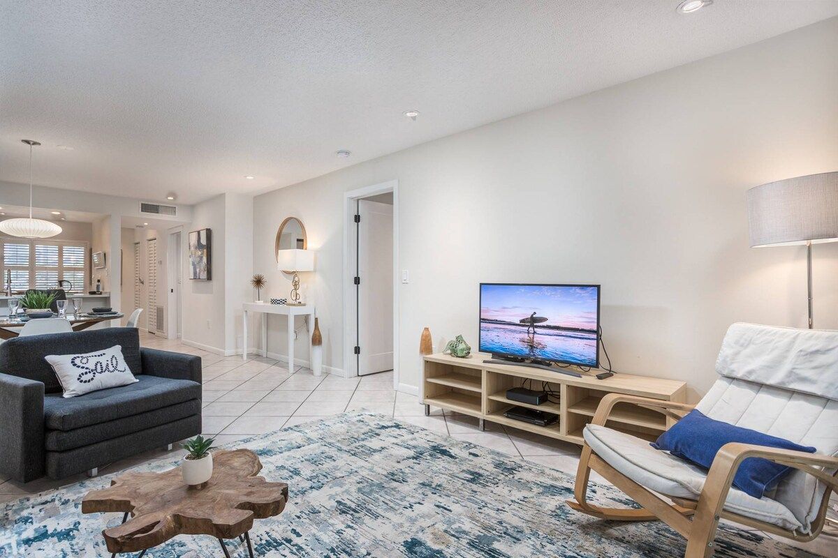 A modern living room with a sofa, a chair, a coffee table, a TV, and a lamp.