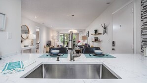 Une cuisine moderne dotée d’un évier double, de deux coins repas et offrant une vue sur le salon.