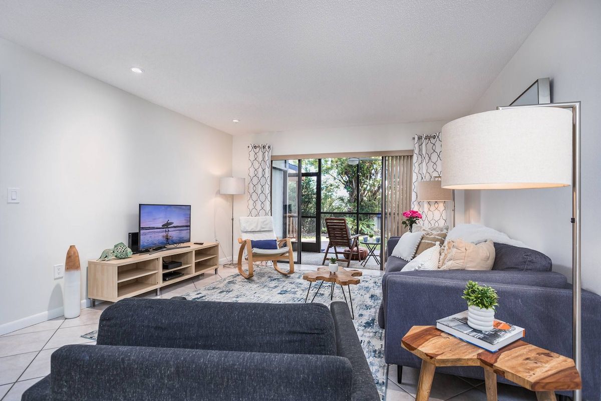 Uma sala de estar moderna com sofá, TV e mesa de centro de madeira.