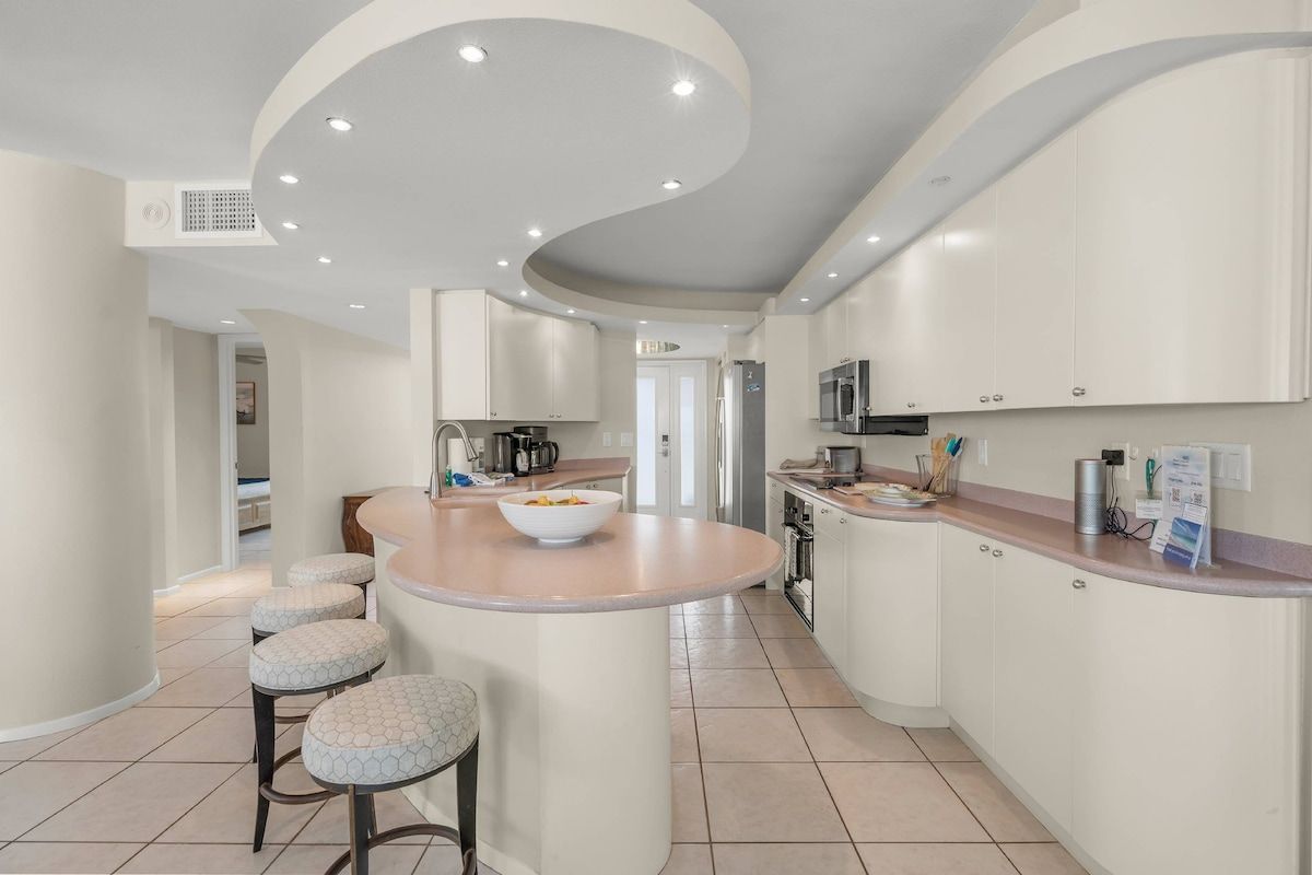 A modern kitchen with a central island, bar stools, and built-in appliances.