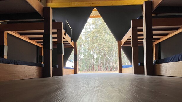 A spacious attic bedroom with a wooden floor, a sloped ceiling, and a view of a forest. - GROUP CAMP ON MURRAY RIVER NEAR ECHUCA / MOAMA (Torrumbarry)