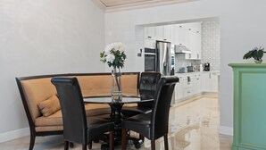 Uma área de refeições com uma mesa redonda, cadeiras pretas e um vaso com flores.