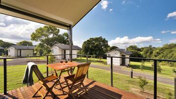 Enjoy a serene view from this deck overlooking a well-maintained lawn and distant buildings.