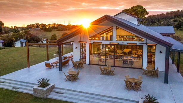 A modern house with a large patio area, large windows, and a dining area. - Beechmont Estate (Beechmont)
