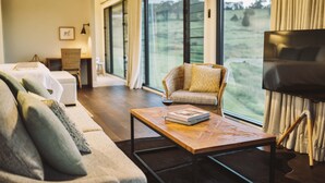 A modern living room with a sofa, armchair, and coffee table. A TV is mounted on the wall, and there is a large window with curtains. - Beechmont Estate (Beechmont)
