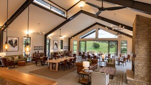 A spacious dining area with high ceilings, large windows, and a stone fireplace. - Beechmont Estate (Beechmont)