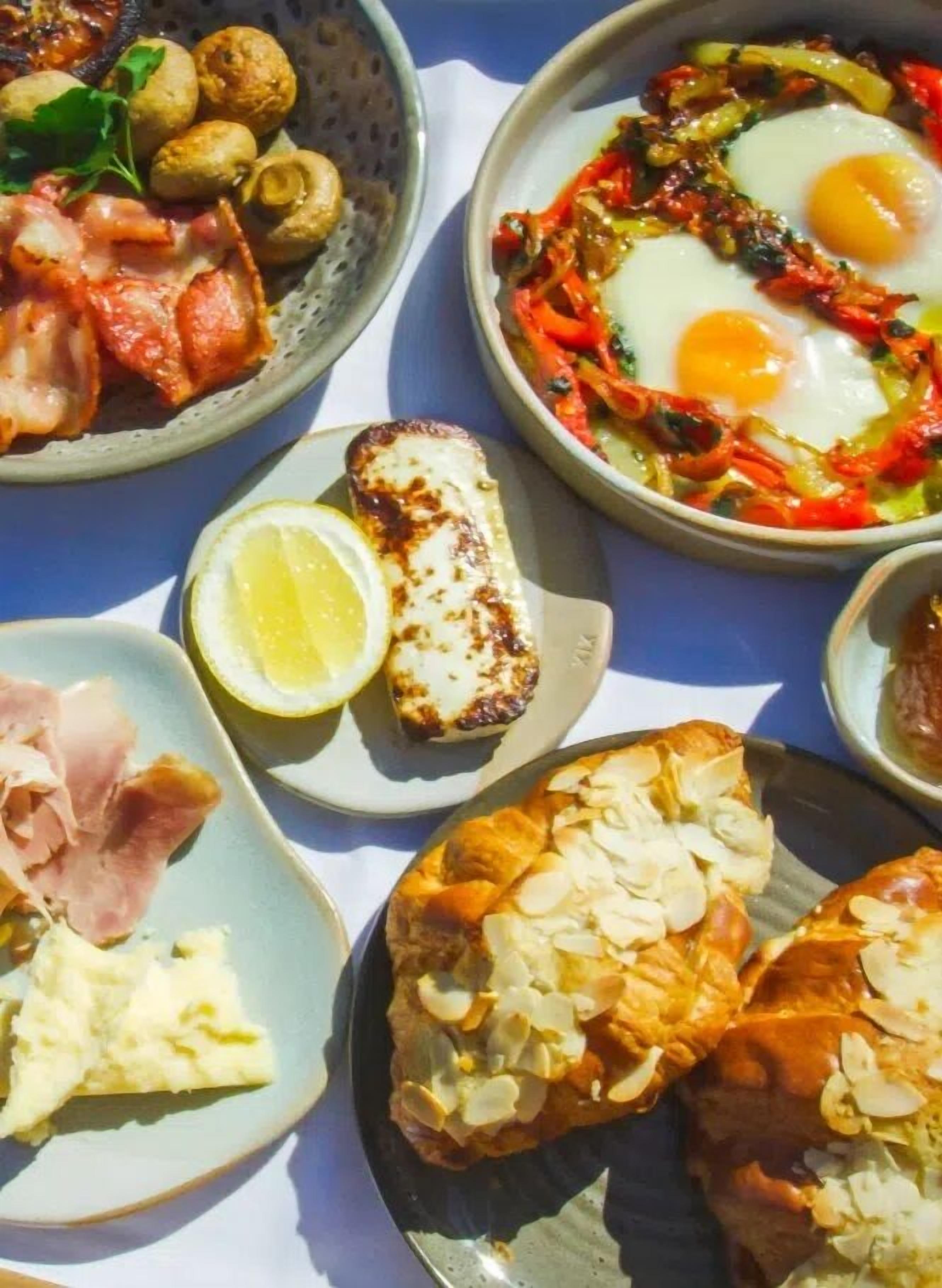 A variety of breakfast dishes including eggs, ham, and pastries on a table.