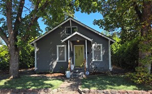 A small, single-story house with a green door, white trim, and a small porch. - The Urban Boho Charmer with Private Backyard, BBQ & Hammock (Roseburg)