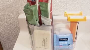 A bathroom with a toothbrush holder containing toothbrushes and toothpaste tubes.