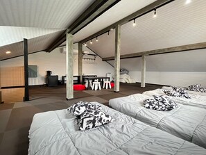 A modern loft-style bedroom with two beds, a red bean bag, and a dining area with a table and chairs. - SAMURISE 81INN (Fujikawaguchiko)