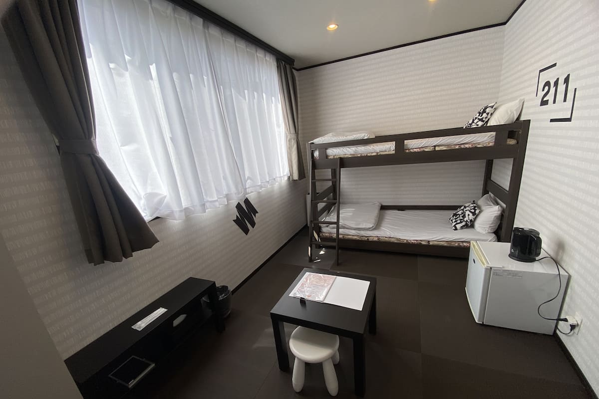 A compact room with a bunk bed, a small desk, and a chair.