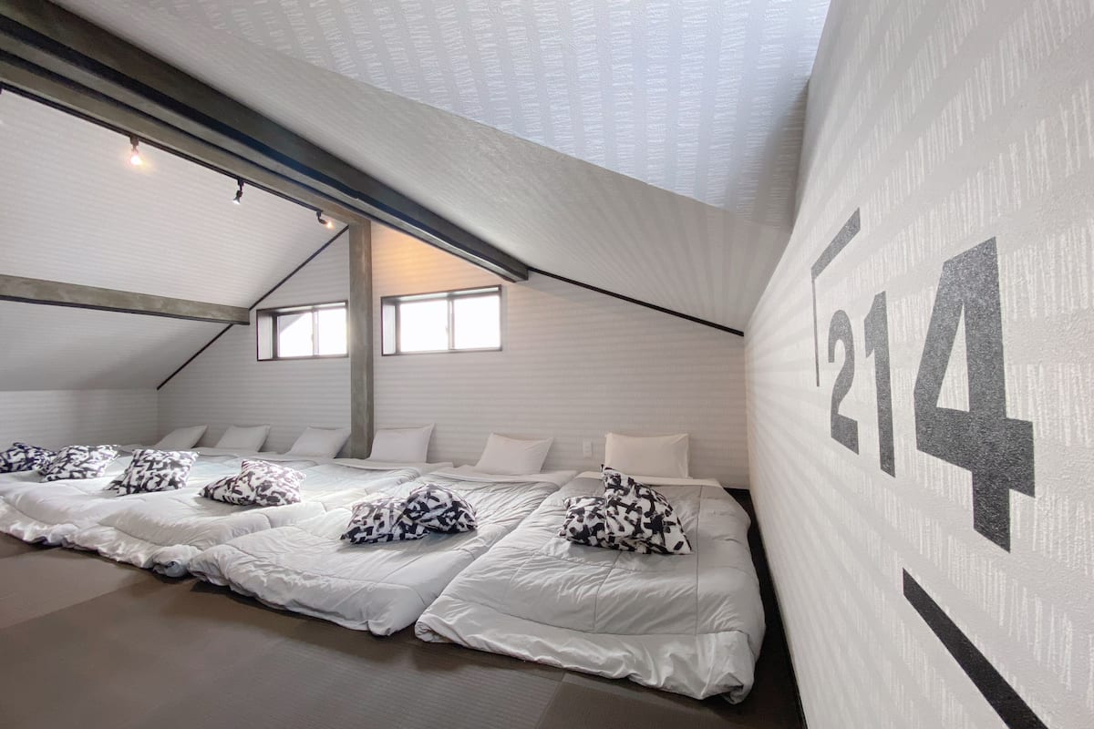 A modern hotel room with a large bed, multiple pillows, and a large number '214' on the wall.