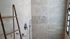 A shower area with a bamboo ladder, a handheld showerhead, and a wall-mounted faucet.