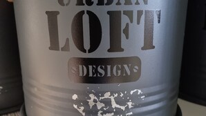 A grey metal container with the text "URBAN LOFT DESIGN" and some peeling paint.