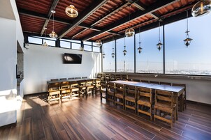 Un comedor amplio con mesas y sillas de madera, ventanas grandes con vistas a la ciudad y lámparas colgantes.