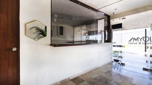 Interior moderno de un hotel con un gran ventanal, una puerta de madera y un ventilador de techo.