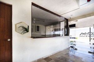 Interior moderno de un hotel con un gran ventanal, una puerta de madera y un ventilador de techo.