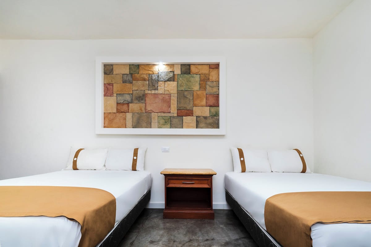 Une chambre d’hôtel avec deux lits, une table de chevet et une œuvre d’art murale en pierre.