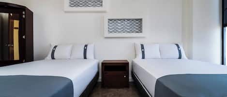 A hotel room with two beds, a nightstand, and two wall-mounted decorative items.
