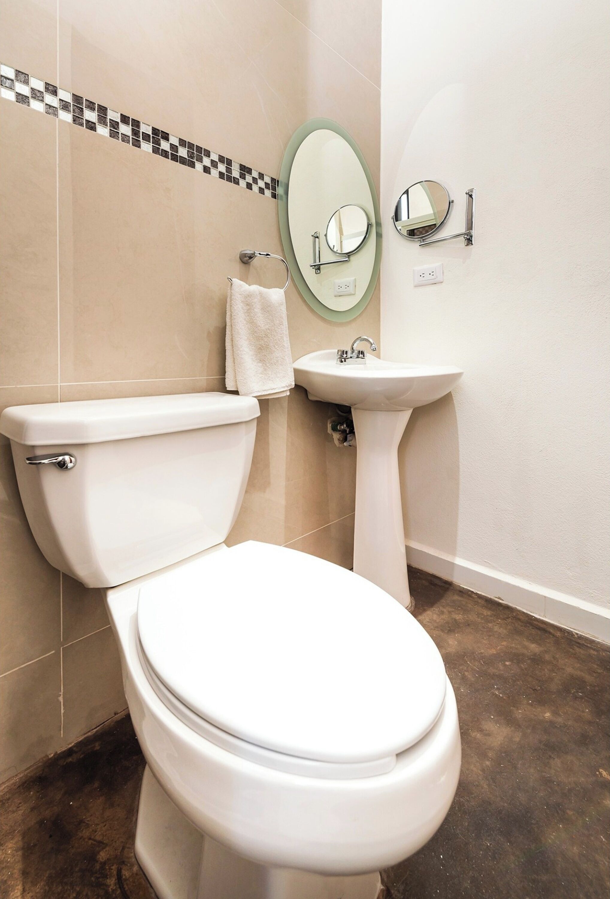 Un baño con inodoro, lavamanos y dos espejos.