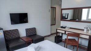 A hotel room with a bed, a desk, a chair, a TV, and a small kitchenette. - Niagara Hotel (Bangkok)