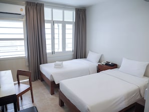 A hotel room with two beds, a desk, and a chair. - Niagara Hotel (Bangkok)