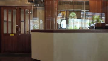 Zona de recepción con mostrador de madera, vitrina de vidrio y puerta con letrero de apertura.